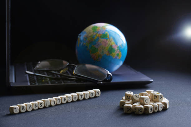 Transliteration lettering next to laptop, glasses and globe. Concept of work on translation and transliteration of educational texts. Selective focusing. Macro