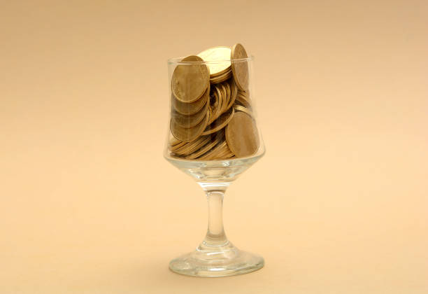 Glass full of Gold Coins - Pouring Money concept.